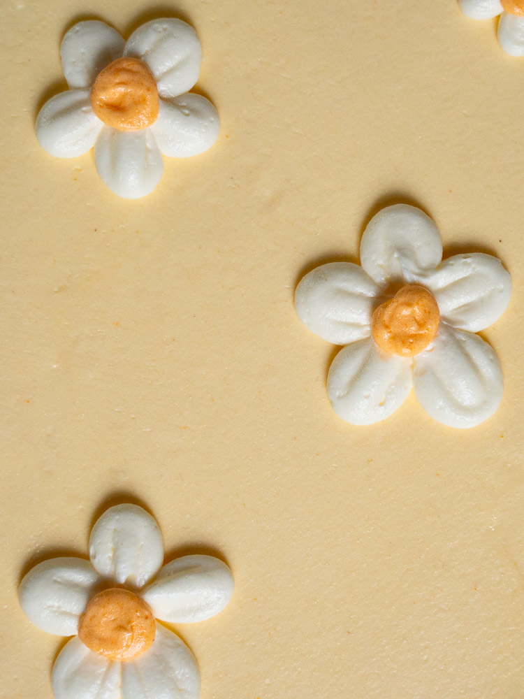 Nahaufnahme der Torte 'Daisy': Gelbe Geburtstagstorte mit individuell gestaltetem, und floralem Design.