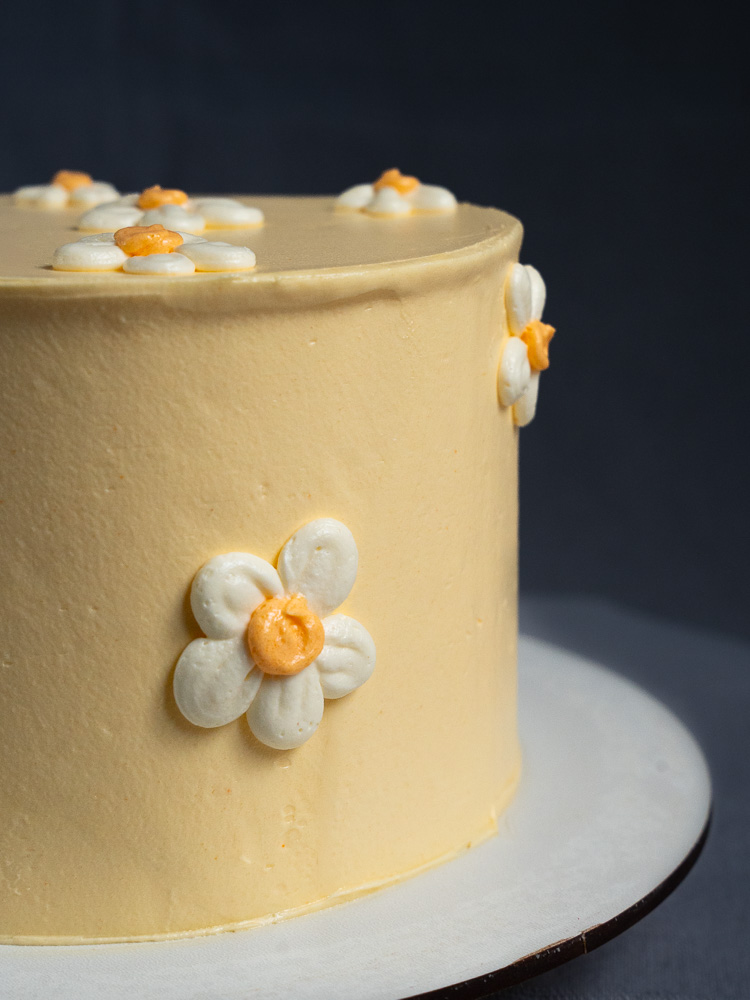 Nahaufnahme der Torte 'Daisy': Gelbe Geburtstagstorte mit individuell gestaltetem, und floralem Design.